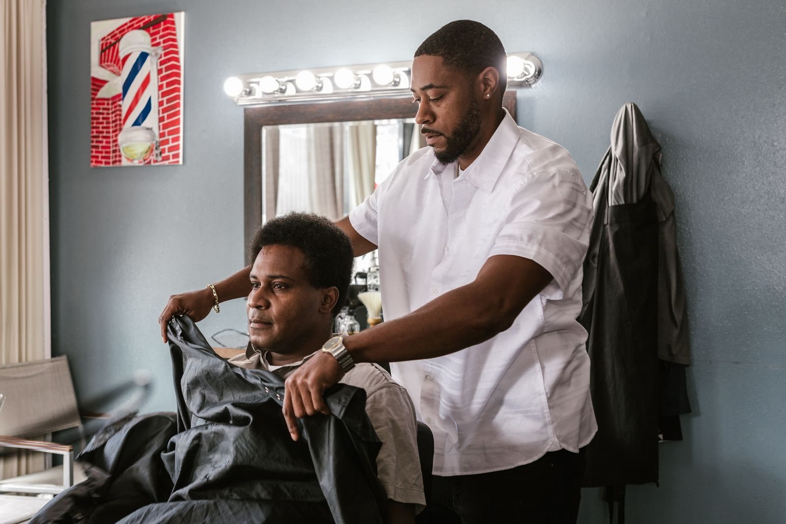 A barbershop owner serving a client in his neighborhood shop