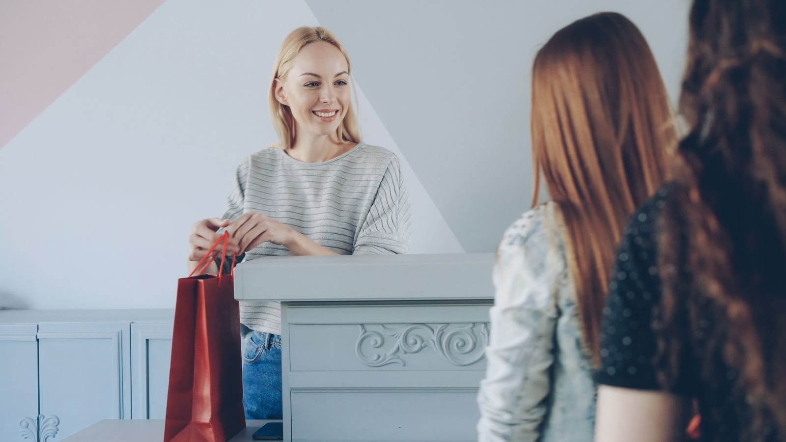 A boutique owner helping a customer choose merchandise at the counter