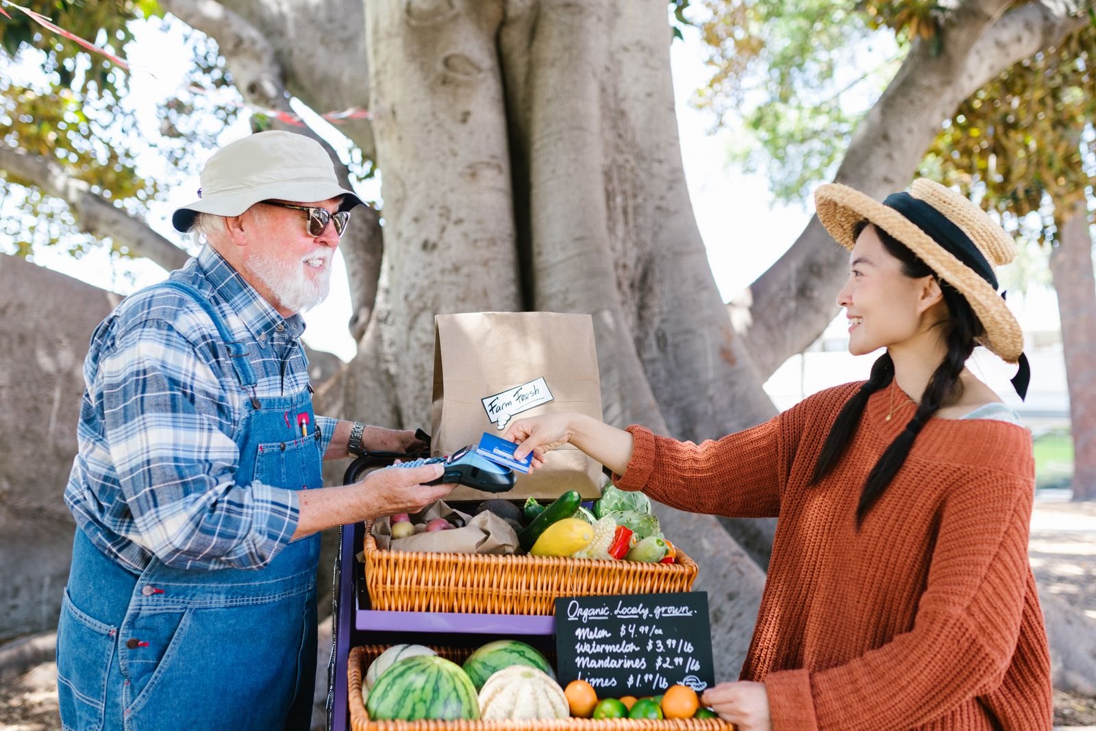 An independent market vendor accepting a card payment from a customer at her produce stand