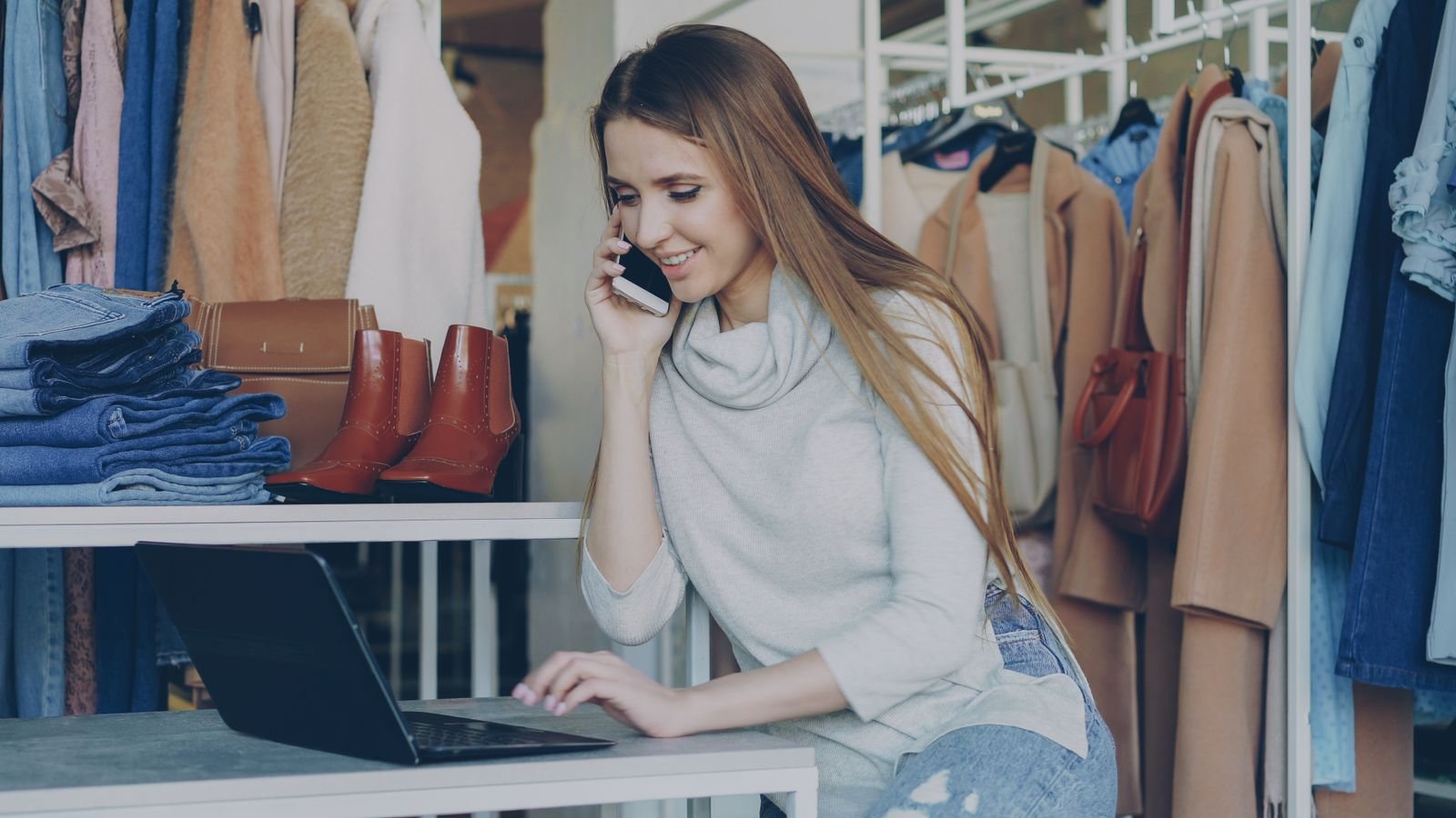 A retail owner speaking with a customer by phone from her shop counter