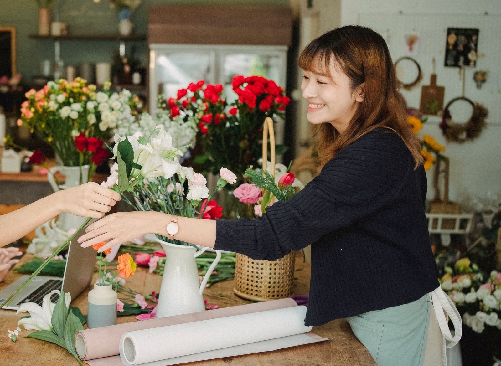 A florist arranging a bouquet at her shop counter