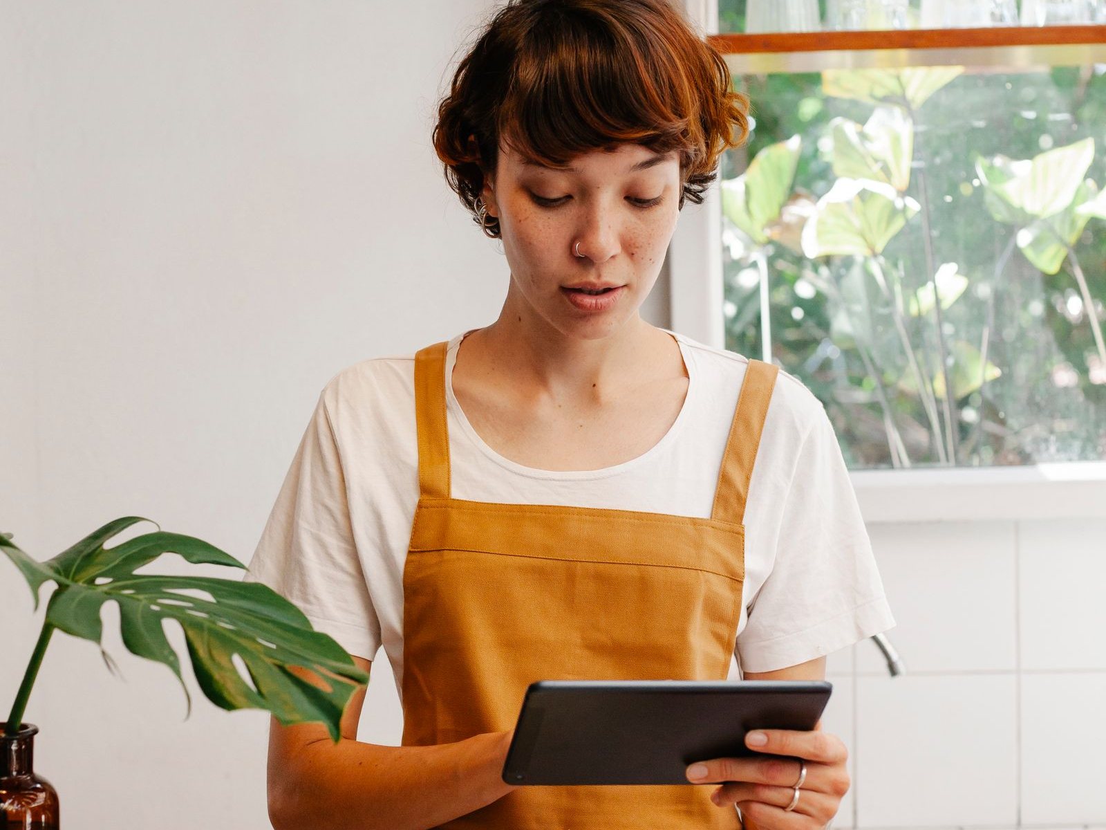 A cafe employee reviewing a customer order on a tablet at the counter