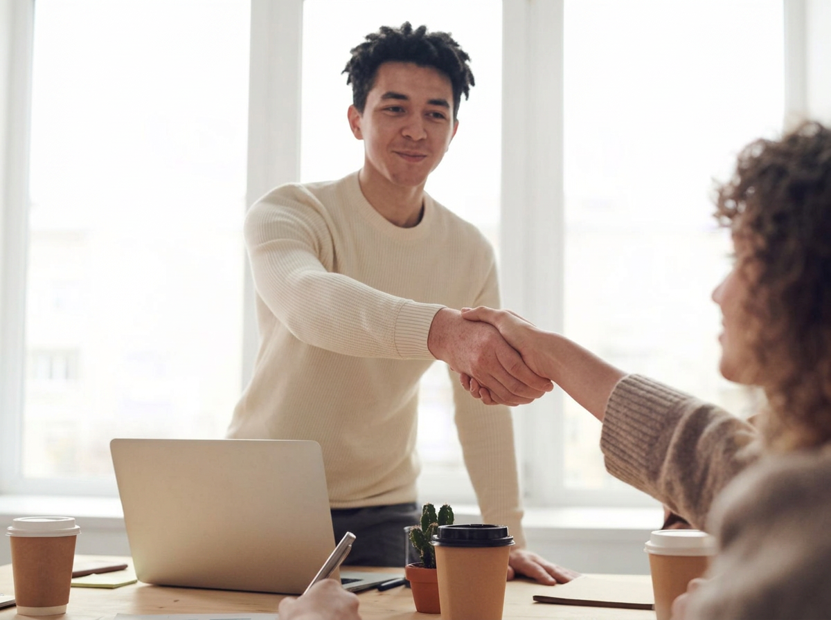 Two small-business professionals shaking hands in a warm, candid moment of partnership