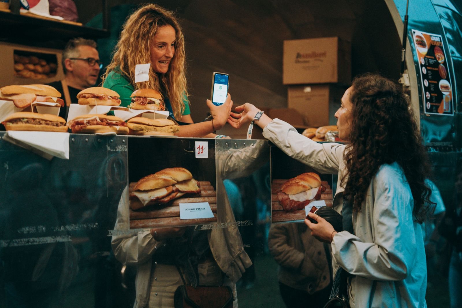 A food truck owner taking a customer's card payment at the service window